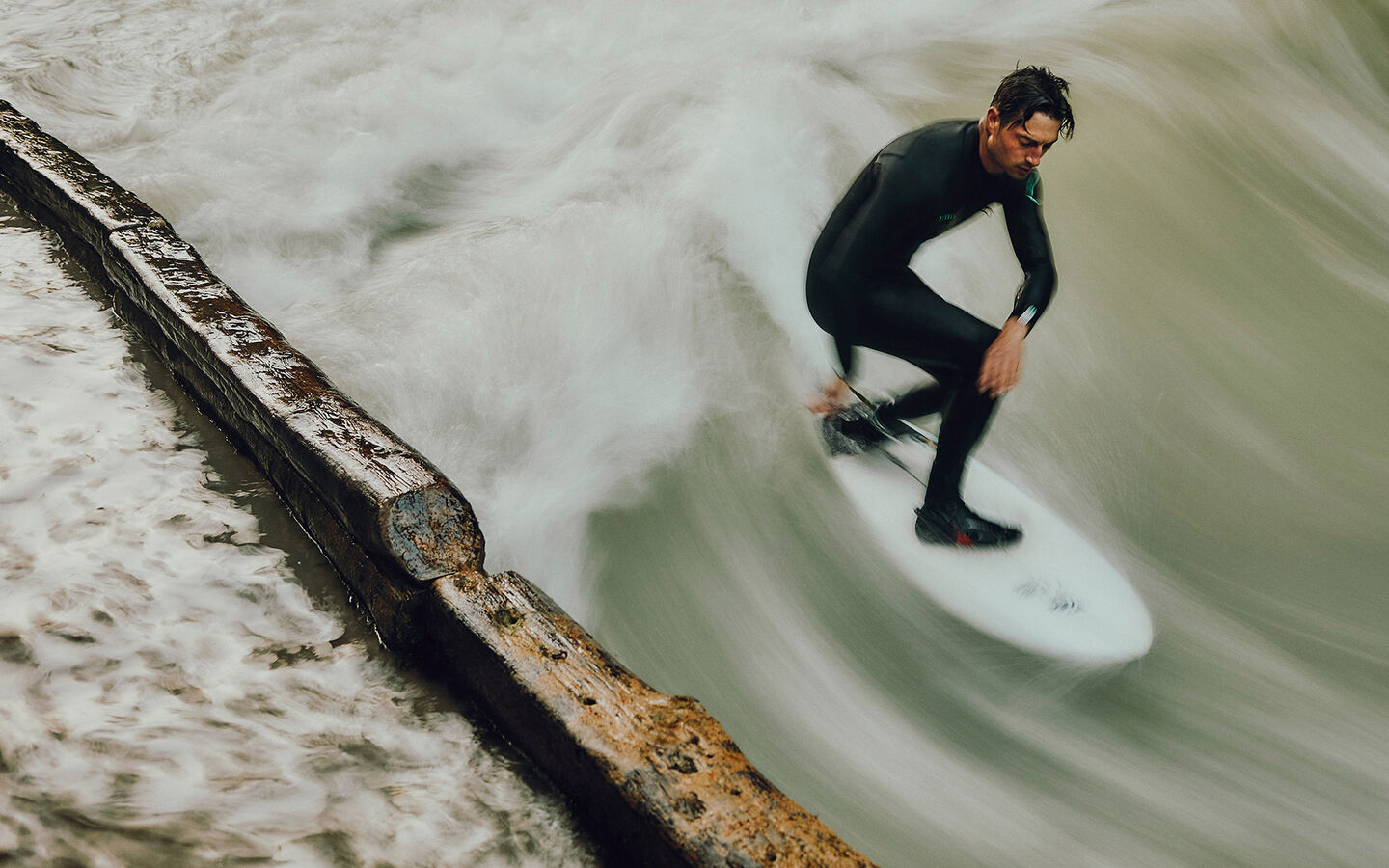 Surfen auf der Münchner Eisbachwelle Sebastian Kuhn steht auf seinem Surfbrett und surft die Münchner Eisbachwelle
