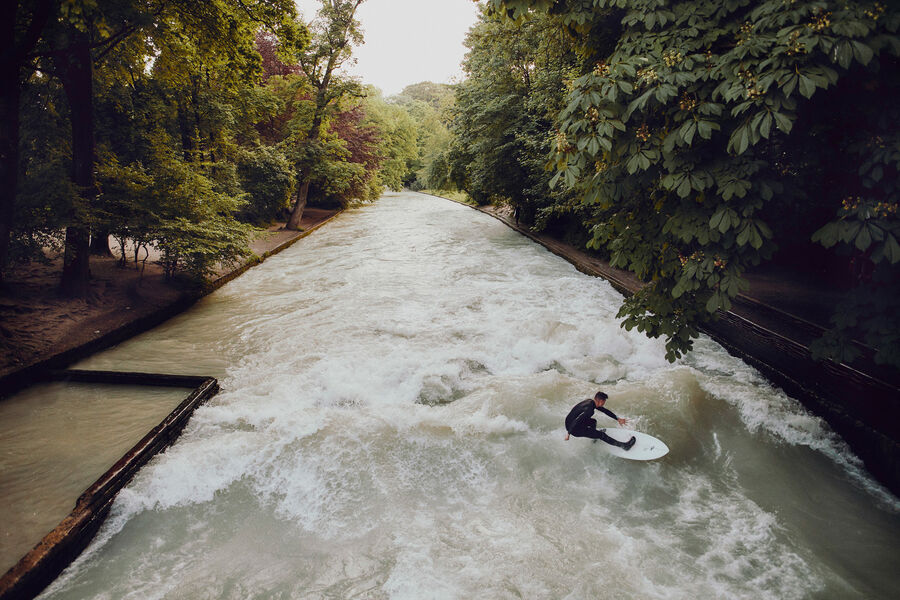 Surfen auf der Münchner Eisbachwelle Der Münchner Eisbach mit seiner Welle und einem Surfer