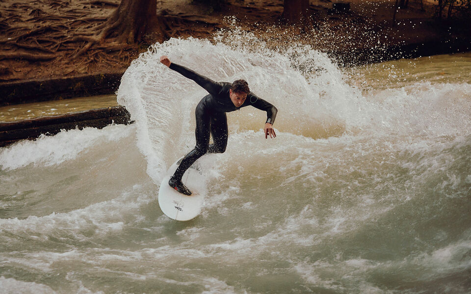 Surfen auf der Münchner Eisbachwelle Sebastian Kuhn nimmt eine Kurve beim Surfen auf der Eisbachwelle