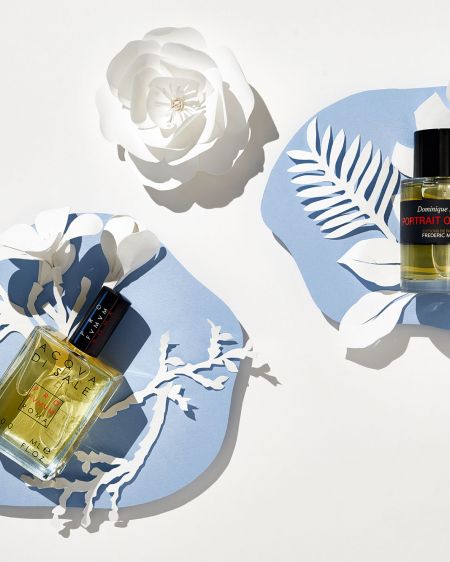 Stillleben mit zwei Parfüms, weißer Papierkunst auf blauen Papierkreisen