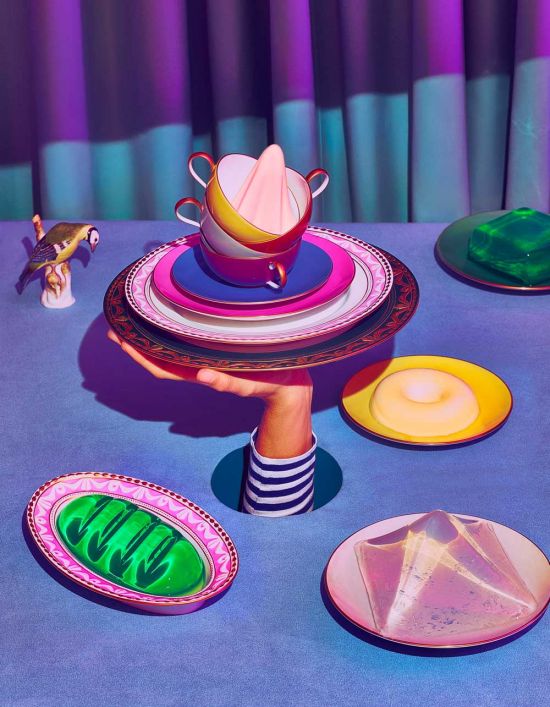 Porzellangeschirr kreativ kombiniert: Fotostrecke im KPM-Magazin WEISS jetzt ansehen Hand hält aufeinander gestapelte Porzellanteller und -tassen