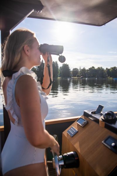 E-Boot fahren auf dem Ammersee für SeeMagazin 2021 Junge Frau am Steuer eines E-Boots schaut durch Fernglas