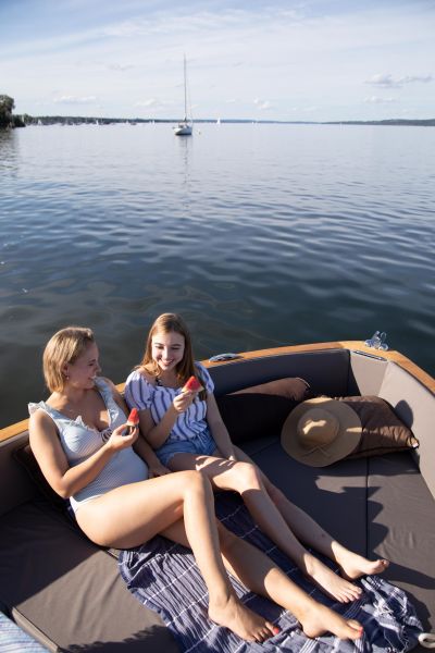 E-Boot fahren auf dem Ammersee für SeeMagazin 2021 Zwei junge Frauen sitzen in Elektroboot und essen Wassermelone